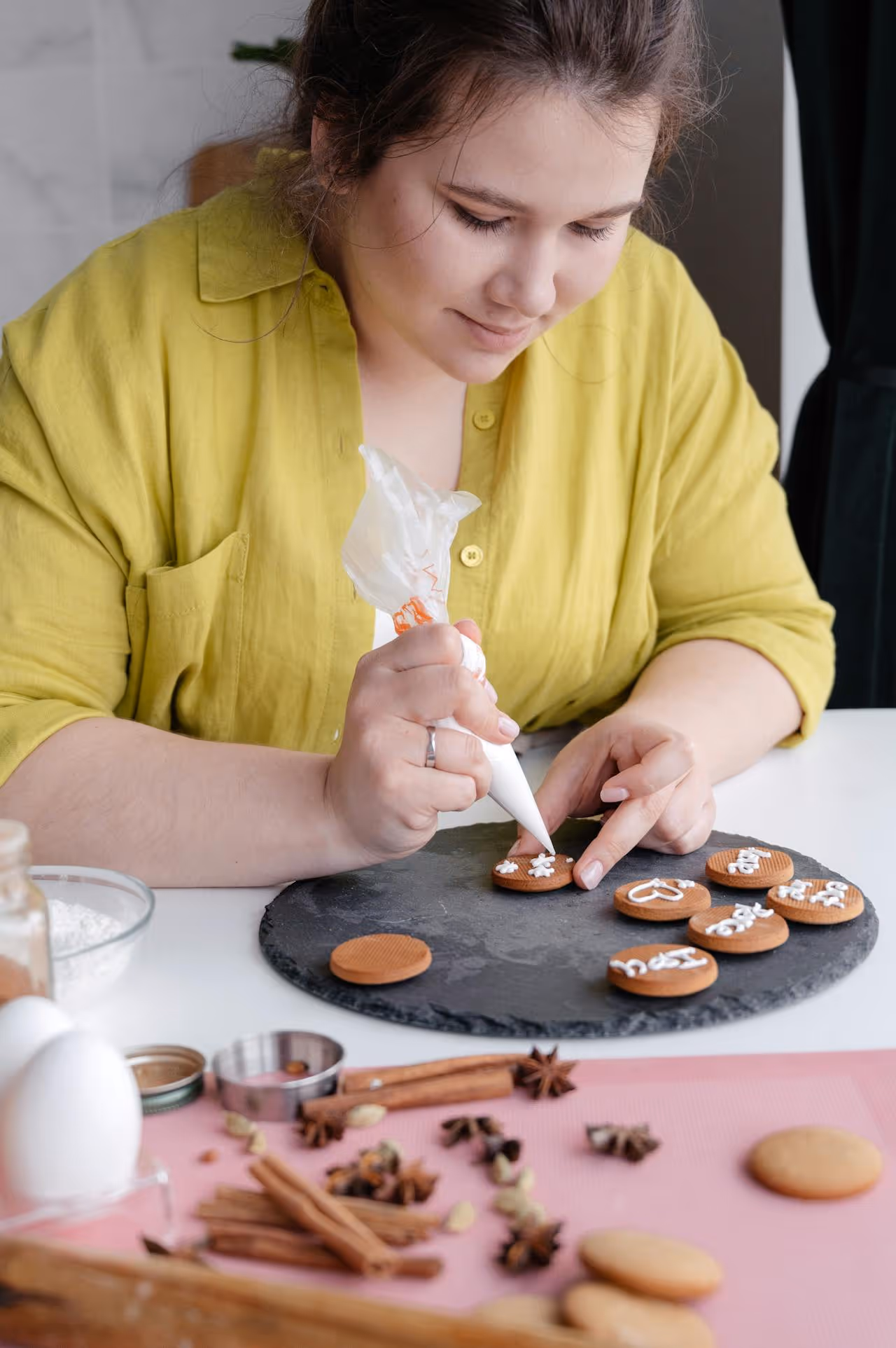 Mary sorrindo em sua confeitaria, decorando um bolo com glacê
